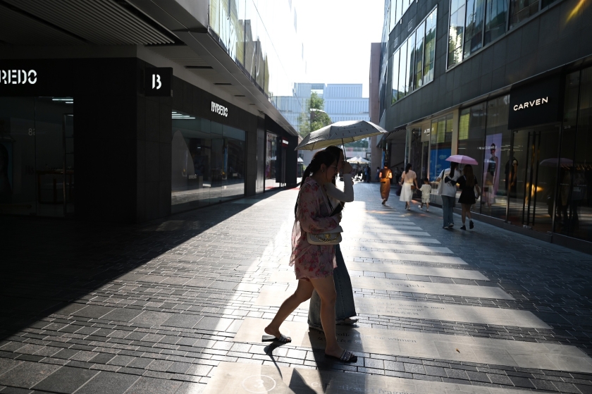 A woman crosses a city street amid hot temperatures