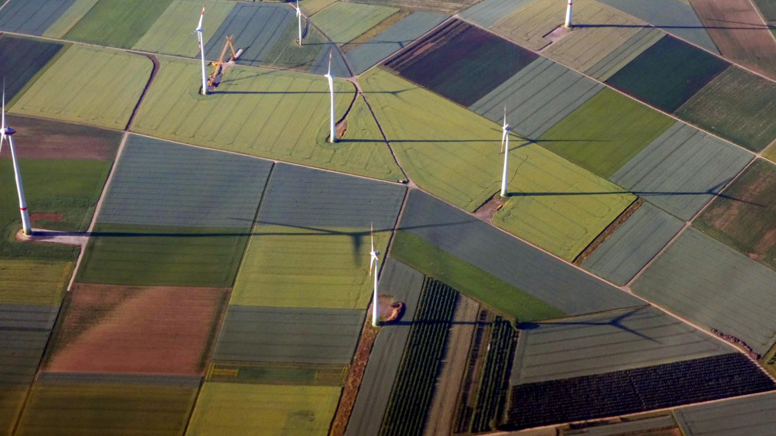 An aerial view of farmland with wind turbines