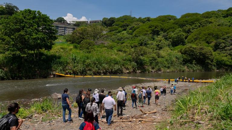 Participants in the Costa Rica City Academy walk down the banks of the Virilla River to see the waste trapping plastic barrier.