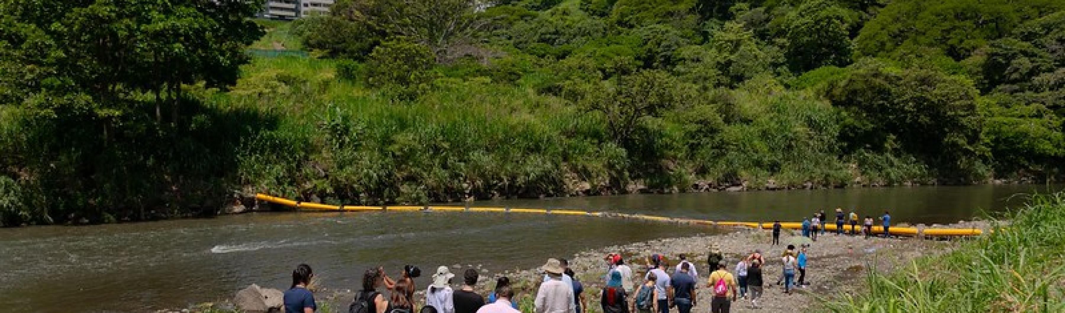 Participants in the Costa Rica City Academy walk down the banks of the Virilla River to see the waste trapping plastic barrier.