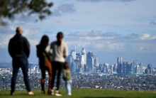 people standing on a green lawn looking at a city